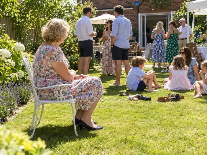 A summer party in a backyard, everyone barefoot on the grass except one older woman in navy pumps